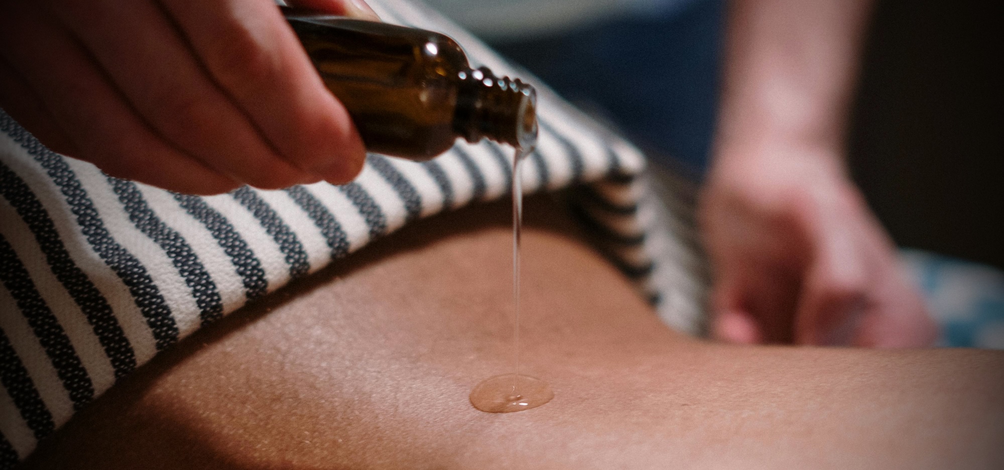 Aceite de masaje cayendo sobre la espalda de una persona recostada en la camilla
